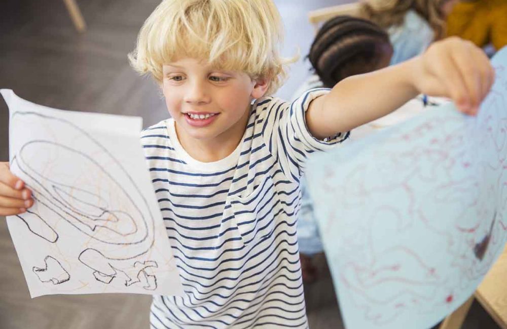 Student showing off drawings in classroom